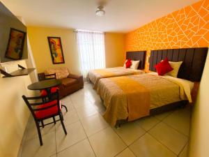 a bedroom with two beds and a table and a chair at Hostal Mayra Breña in Lima
