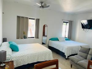 a bedroom with two beds and a chair and a couch at rooms7 in Bacalar