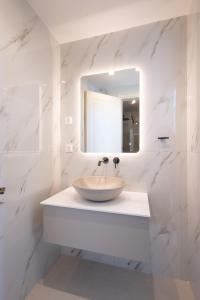 a white bathroom with a sink and a mirror at Promenade Chios Port Residences in Chios