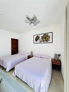 een slaapkamer met twee bedden en een plafondventilator bij rooms7 in Bacalar