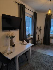 a living room with a white table and a tv at Studio am Waldrand in Bad Hersfeld +8 photos