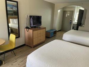 una camera d'albergo con due letti e una TV a schermo piatto di Days Inn by Wyndham Dallas Plano a Plano