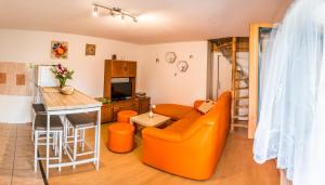 a living room with an orange couch and a kitchen at Malovaný dvůr in Dolní Dunajovice