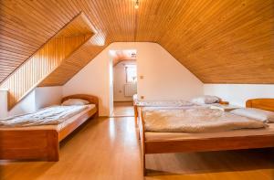 two beds in a room with a wooden ceiling at Malovaný dvůr in Dolní Dunajovice +17 photos
