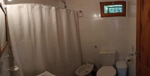 a bathroom with a white shower curtain and a toilet at La Rubina in Villa Ventana +29 photos