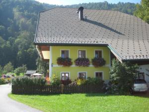 a yellow house with flower boxes on the roof at Biobauernhof Hauserbauer in Hintersee