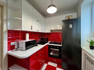 a red kitchen with white cabinets and a black refrigerator at Chișinău Airport Comfort in Chişinău +11 photos