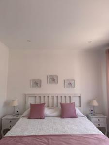a white bedroom with a large bed with pink pillows at Casa Ventura in Lagos +10 photos