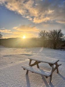 Een bankje in de sneeuw met de zon op de achtergrond. bij The Pods at 7 Black Crofts in Oban