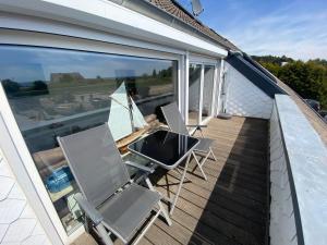 a balcony with two chairs and a television on it at Küstenbude Ostseestübchen in Grömitz