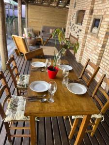 a wooden table with plates and glasses on a patio at Hospedaria LARENA in Florianópolis