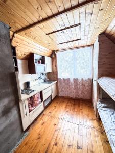 a kitchen with wooden floors and a large window at Anetes pirts in Jaunanna
