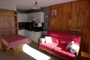 a living room with a red couch and a kitchen at Le refuge 66 in Saint-Aventin