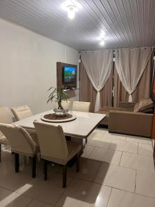 a living room with a table and chairs and a tv at Casa com três quartos, piscina e área Gourmet in Torres
