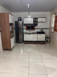 a kitchen with a stainless steel refrigerator and white cabinets at Casa com três quartos, piscina e área Gourmet in Torres