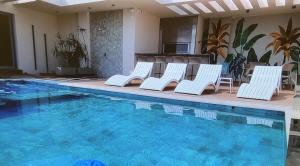 a group of white chairs sitting next to a swimming pool at Lujoso Departamento con Garage in Caña de Castilla