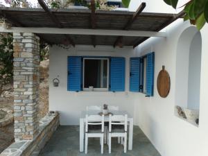 a table and chairs on a patio with blue shutters at Gaia house, Ios Greece in Tzamaria