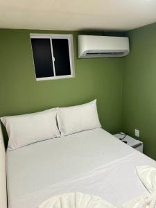 a bedroom with a white bed with a green wall at Pousada Oxente Carioca in João Pessoa