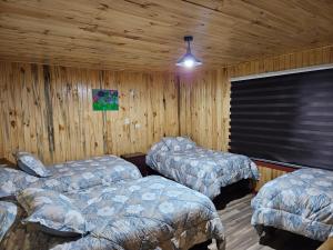 two beds in a room with wooden walls at Las Victorias in Salto del Laja +11 photos