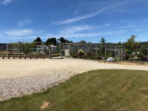 a garden with a greenhouse in the background at Just Dean Motueka in Lower Moutere