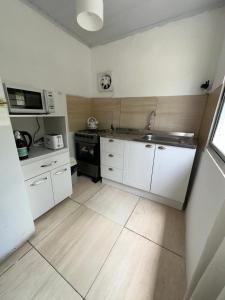 a kitchen with white cabinets and a sink and a microwave at Moramay 2 in Punta del Este +4 photos