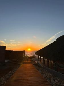 a sunset on the beach with a wooden pathway at Hotel Calma Celesti in Perihuete