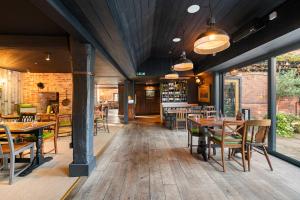a restaurant with wooden tables and chairs and windows at Blacksmiths Cottage by Birch Stays in Needwood