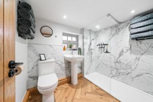 a bathroom with a white toilet and a sink at Blacksmiths Cottage by Birch Stays in Needwood +26 photos