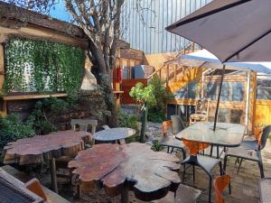 an outdoor patio with tables and chairs and an umbrella at HOSTEL SAKAR QUINTERO Beach in Quintero
