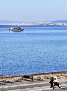 a couple of people walking by the water with a boat at Niko's Apartment - Beautiful Sea View Apartment ! in Perea