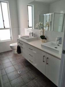 a white bathroom with two sinks and a toilet at 3rd On Troon in Normanville +19 photos