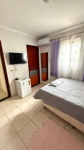a bedroom with a bed and a tv in it at Suítes Santa Luzia in Trindade