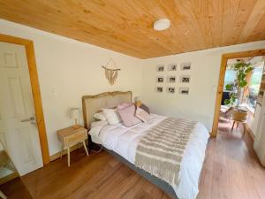 a bedroom with a bed and a wooden ceiling at Cabaña de Montaña con Río in Puhala