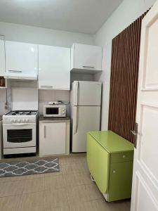 a kitchen with white appliances and a green stool at Appartement central et spacieux in Monastir +1 photo