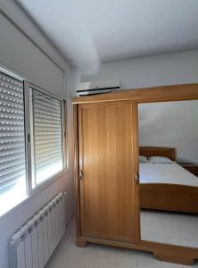 a bedroom with a bed and a wooden cabinet at Appartement central et spacieux in Monastir