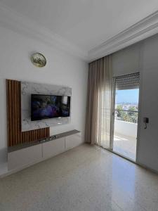 a white room with a tv and a window at Appartement central et spacieux in Monastir