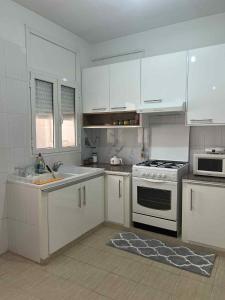a kitchen with white cabinets and a stove top oven at Appartement central et spacieux in Monastir