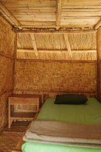 a room with a green bed in a straw hut at Betelnut Eco-Lodge Sumba in Lambatama +66 photos