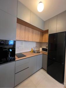 a kitchen with a black refrigerator and wooden cabinets at White Homes 1BR - Central Point in Podgorica
