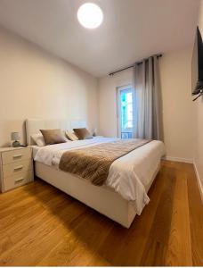 a bedroom with a large bed and a television at White Homes 1BR - Central Point in Podgorica +29 photos