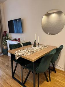 a dining room table with green chairs and a mirror at Royal apartman Zlatibor in Palisat