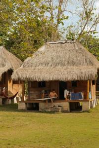 a hut with a man sitting outside of it at Betelnut Eco-Lodge Sumba in Lambatama