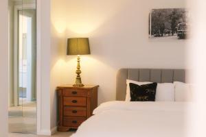 a bedroom with a bed and a lamp on a night stand at Hampton Luxe Designer Retreat with Park Views in Melbourne