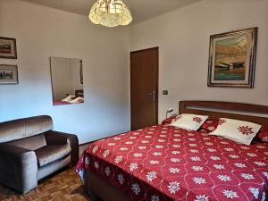 a bedroom with a bed and a chair and a mirror at Casa Lassù in Pieve di Cadore