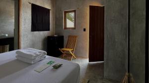 a bedroom with a bed and a chair and a window at Lalito in Zipolite +24 photos