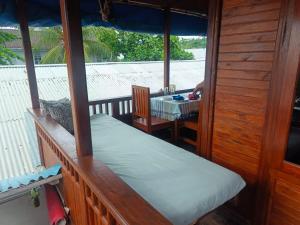 a porch of a house with a table and a bed at Heiner Beach Homestay in Bunaken