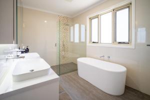 a white bathroom with a tub and a sink at Hampton Luxe Designer Retreat with Park Views in Melbourne