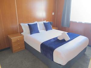 a bedroom with a large bed with blue and white pillows at Cumberland Motel in Dunedin