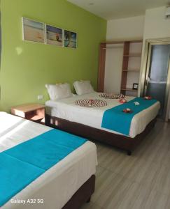 zwei Betten in einem Zimmer mit grünen Wänden in der Unterkunft Nadi Fancy Hotel in Nadi