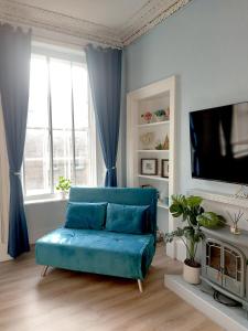 a living room with a blue couch and a tv at Spacious Victorian Apartment in Edinburgh City in Edinburgh